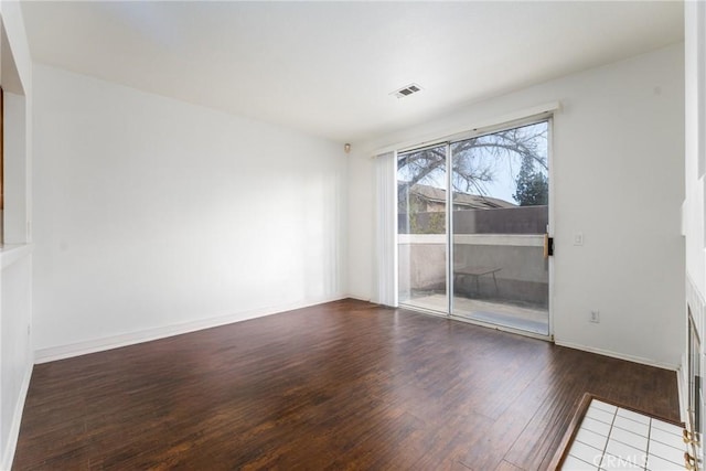 empty room featuring visible vents, hardwood / wood-style flooring, and baseboards