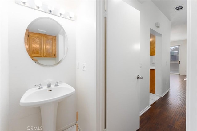 bathroom featuring baseboards, visible vents, wood finished floors, and a sink