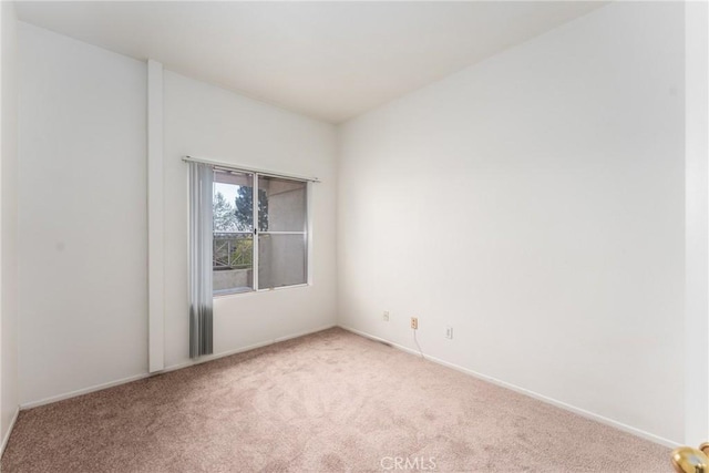 carpeted empty room featuring baseboards