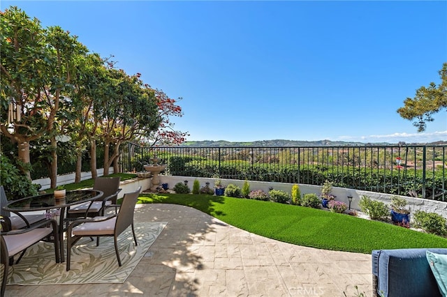 view of patio with outdoor dining space, a mountain view, and a fenced backyard