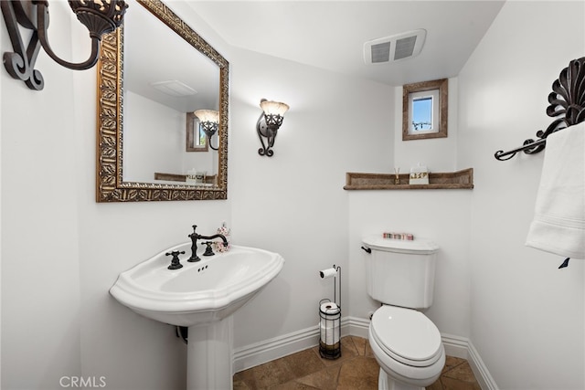 half bathroom featuring toilet, baseboards, and visible vents