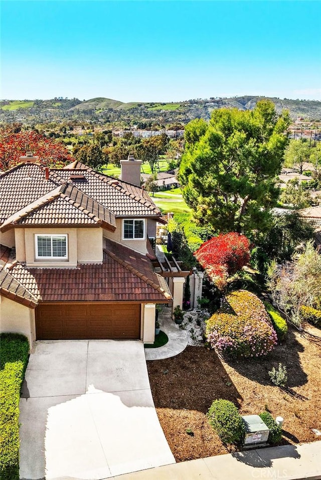 mediterranean / spanish house with a tiled roof, driveway, a chimney, and a garage