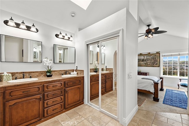 bathroom with a sink, stone tile floors, lofted ceiling, and ensuite bathroom