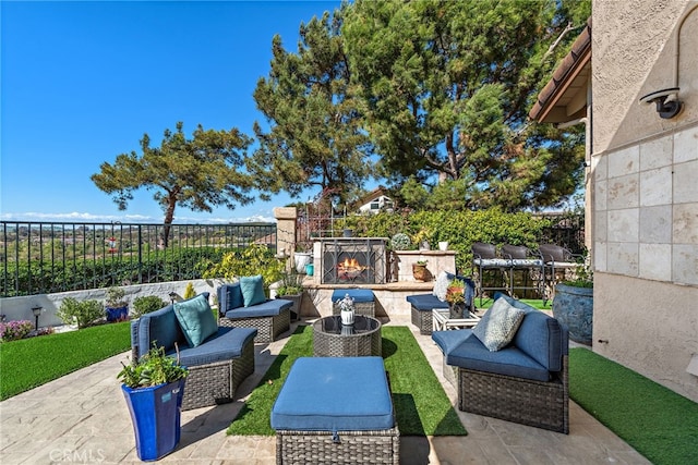 view of patio with an outdoor living space with a fireplace and fence