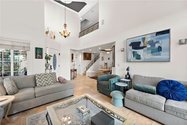 living room featuring stairs, a high ceiling, a notable chandelier, and visible vents