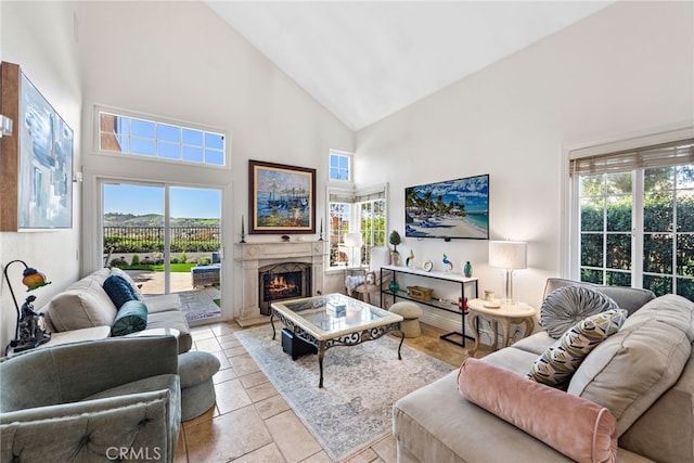 living area featuring a lit fireplace, light tile patterned floors, high vaulted ceiling, and plenty of natural light