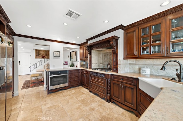 kitchen featuring a sink, stainless steel appliances, stone tile floors, visible vents, and backsplash