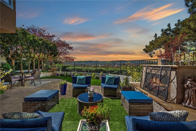 patio terrace at dusk featuring outdoor dining space, fence, and an outdoor living space