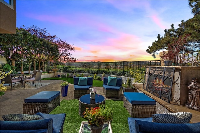 patio terrace at dusk with a fenced backyard, outdoor dining area, and outdoor lounge area