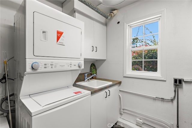 laundry area featuring cabinet space, a sink, and stacked washer and dryer