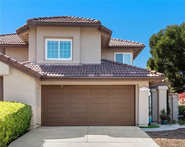 view of front facade with concrete driveway, a tiled roof, and stucco siding