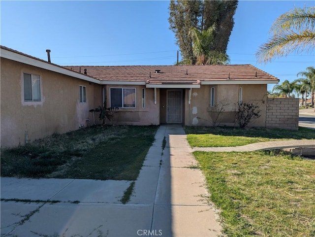 single story home with a tile roof, a front yard, and stucco siding