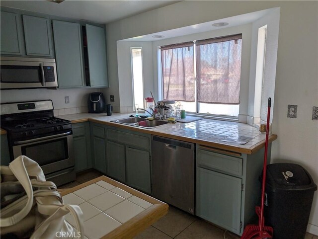 624 Kesha Ct, San Jacinto, CA 92583 - kitchen with appliances with stainless steel finishes, a sink, tile counters, and light tile patterned flooring