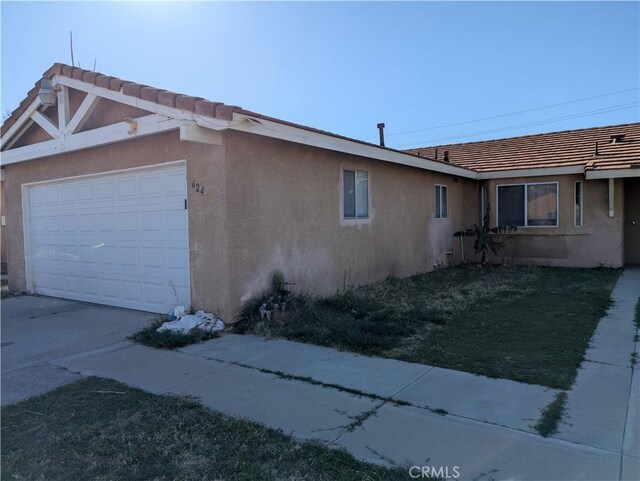 624 Kesha Ct, San Jacinto, CA 92583 - view of side of property with stucco siding, an attached garage, a tiled roof, and concrete driveway