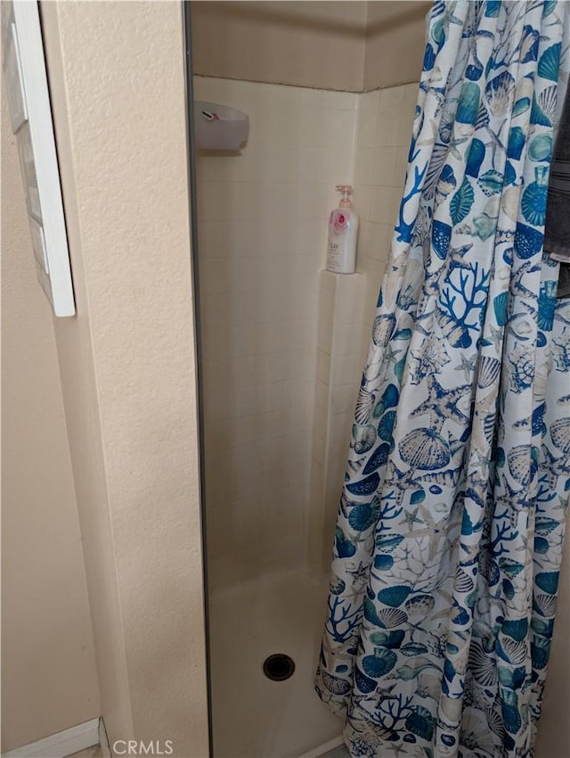 full bath with baseboards and tiled shower