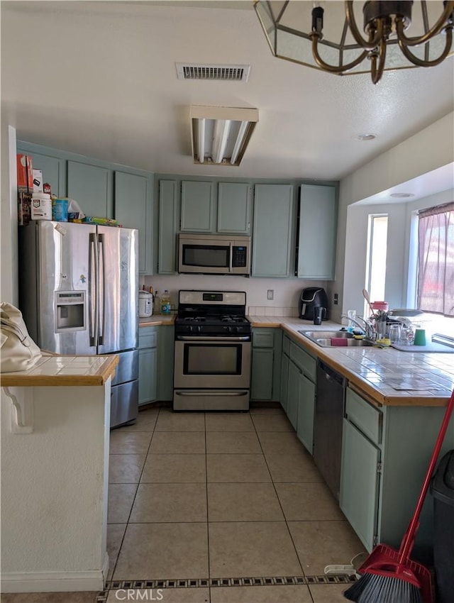 kitchen featuring stainless steel appliances, a peninsula, a sink, visible vents, and light tile patterned floors