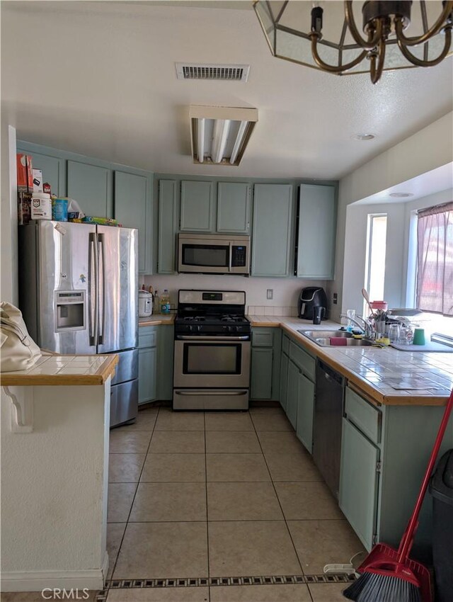624 Kesha Ct, San Jacinto, CA 92583 - kitchen with appliances with stainless steel finishes, a sink, a peninsula, light tile patterned floors, and a chandelier