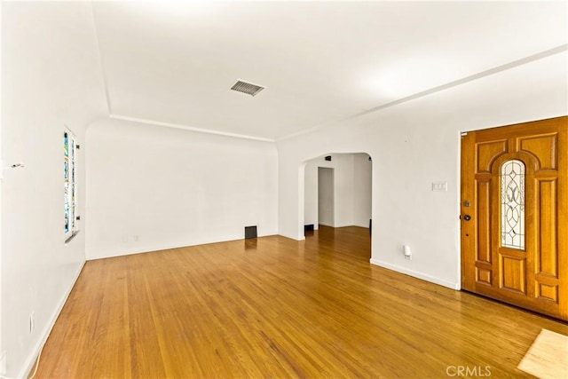 interior space featuring arched walkways, wood finished floors, and visible vents