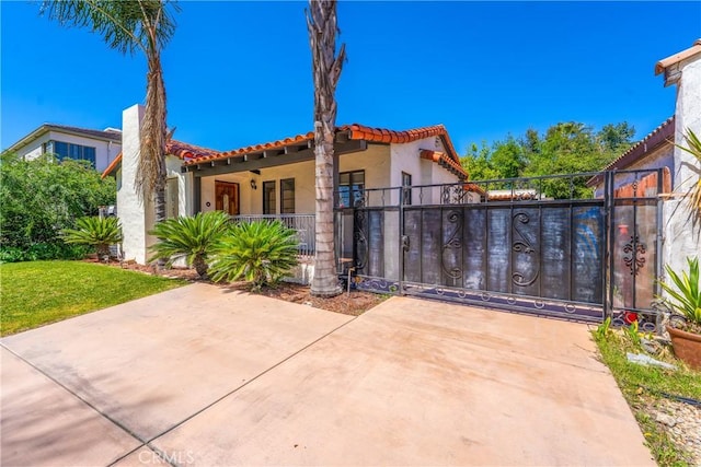 view of front facade featuring a tiled roof, stucco siding, fence, and a gate