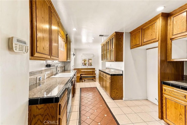 kitchen featuring a sink, light tile patterned floors, brown cabinetry, and recessed lighting