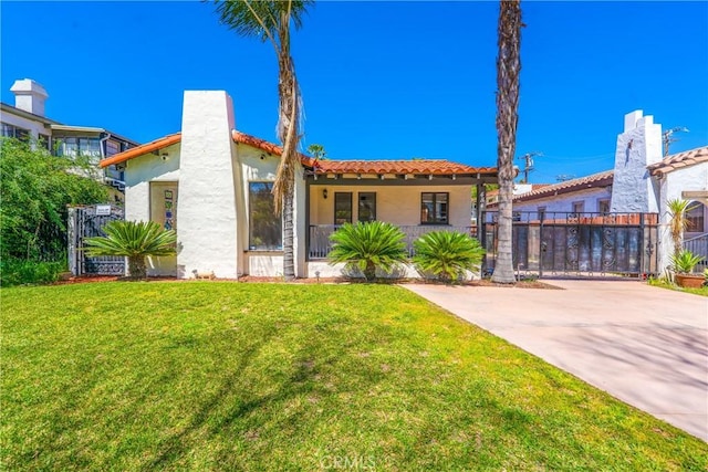 mediterranean / spanish home featuring a front lawn, fence, a gate, and stucco siding
