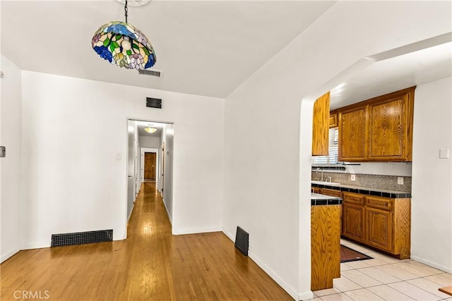 kitchen with visible vents, baseboards, brown cabinetry, and tile counters