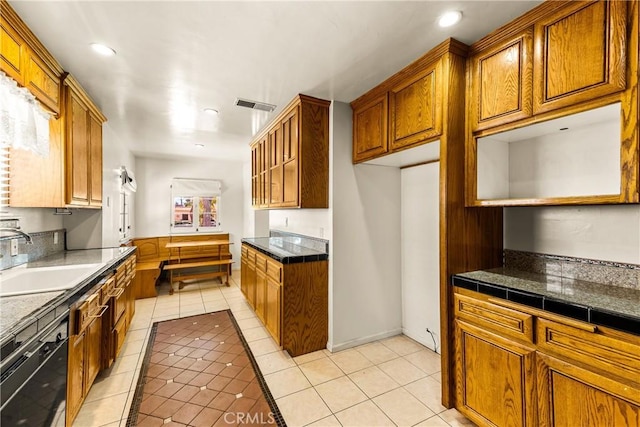 kitchen with visible vents, light tile patterned floors, dishwasher, a sink, and brown cabinetry