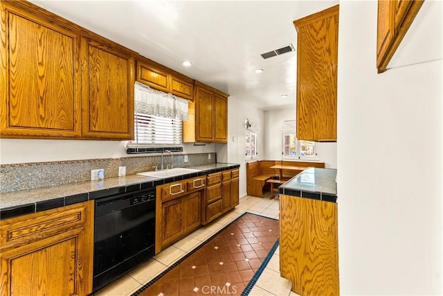 kitchen featuring light tile patterned floors, visible vents, brown cabinetry, dishwasher, and a sink