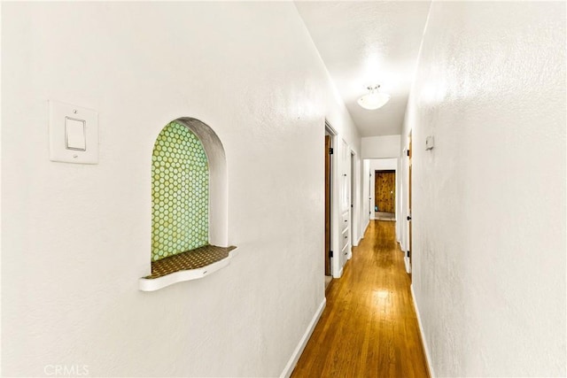 hallway featuring baseboards and wood finished floors
