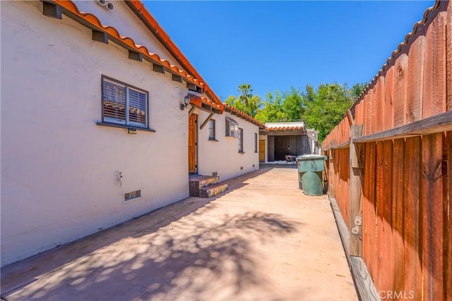 view of home's exterior with a patio, stucco siding, and fence