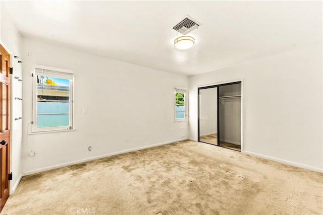 unfurnished bedroom featuring a closet, carpet, visible vents, and baseboards