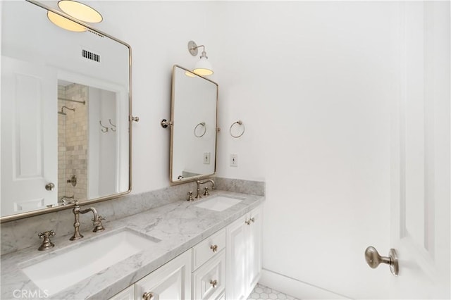 bathroom with double vanity, visible vents, a shower, and a sink