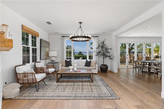 living area with baseboards, an inviting chandelier, recessed lighting, visible vents, and wood finished floors