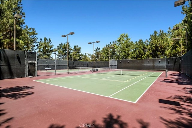 view of tennis court featuring community basketball court and fence