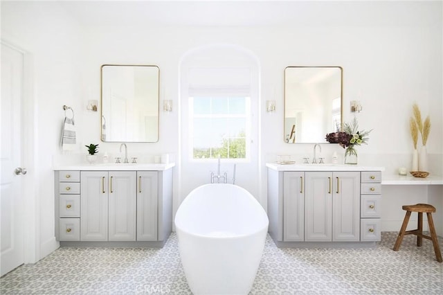 bathroom with a freestanding tub, a sink, and two vanities