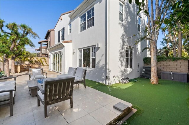 rear view of house featuring a patio area, stucco siding, central AC, and fence