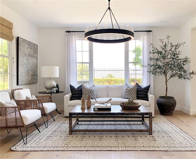 living room with baseboards, a chandelier, and wood finished floors
