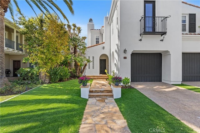 mediterranean / spanish-style house featuring stucco siding, a front lawn, an attached garage, a chimney, and driveway
