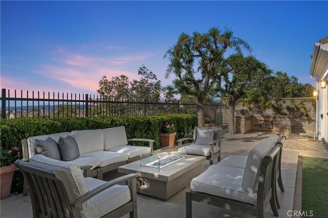 patio terrace at dusk with an outdoor living space with a fire pit and a fenced backyard