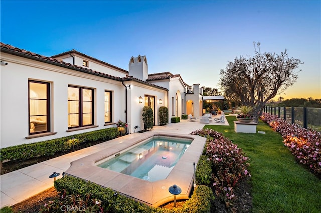 back of house with a patio, an in ground hot tub, a tile roof, a yard, and fence