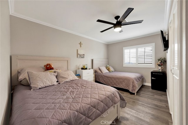 bedroom with wood finished floors, crown molding, baseboards, and ceiling fan