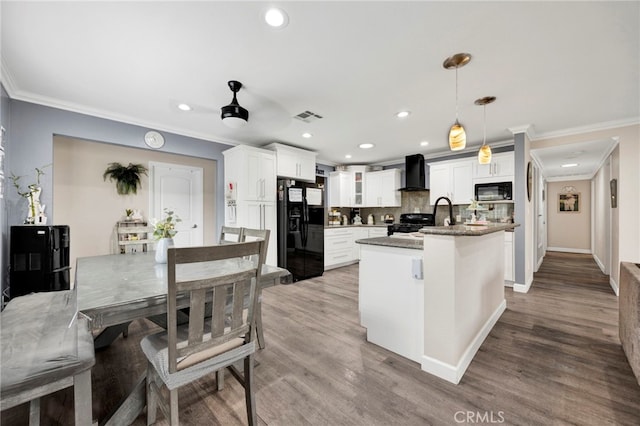 kitchen featuring black appliances, wall chimney exhaust hood, ornamental molding, and visible vents