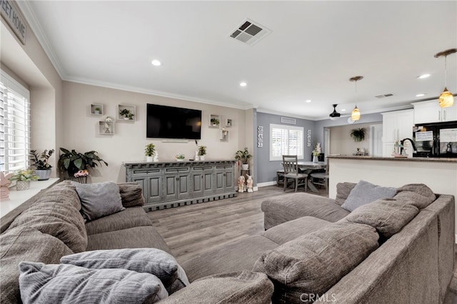 living room featuring recessed lighting, visible vents, light wood finished floors, and ornamental molding