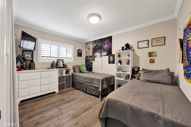 bedroom with wood finished floors and crown molding