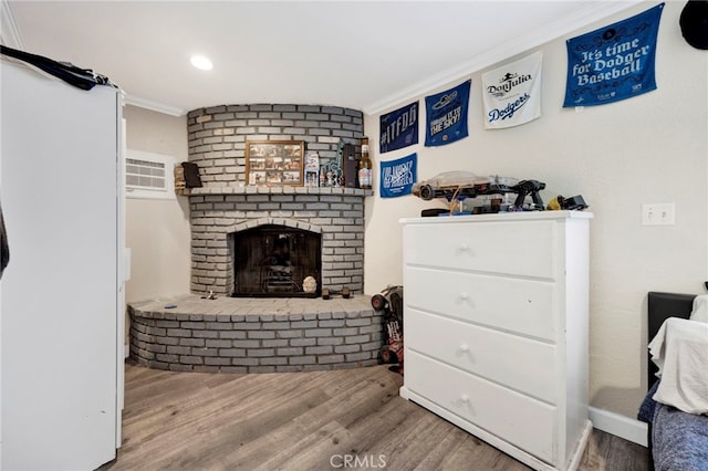 living area featuring ornamental molding, a brick fireplace, wood finished floors, and recessed lighting