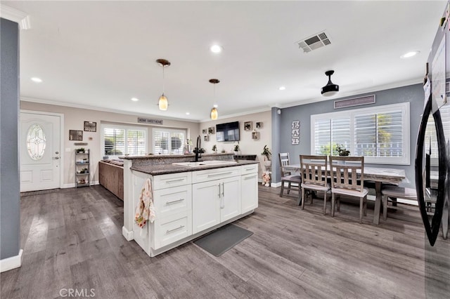 kitchen featuring dark wood-style flooring, crown molding, a sink, white cabinetry, and visible vents