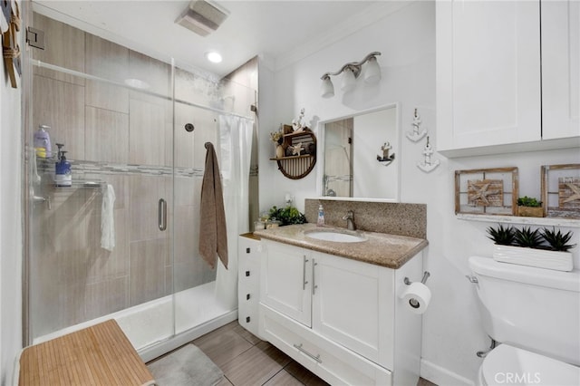 full bath with toilet, vanity, ornamental molding, and a stall shower