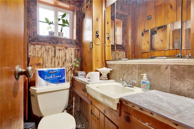 half bathroom featuring toilet, vanity, and decorative backsplash