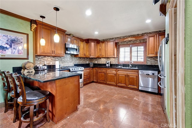 kitchen with a peninsula, a sink, brown cabinetry, and appliances with stainless steel finishes