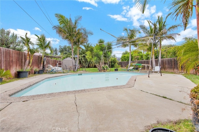 view of pool featuring an outbuilding, a fenced backyard, a shed, and a patio